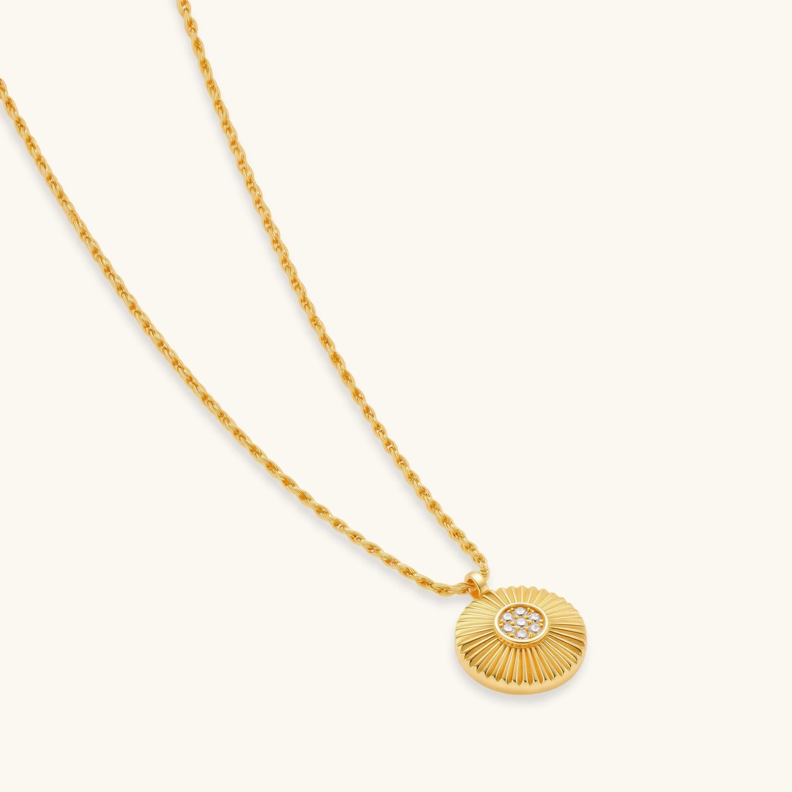 Gold-plated sterling silver necklace with sunburst pendant featuring radiating lines and cubic zirconia center stones